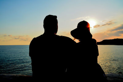 Silhouette couple against sea during sunset