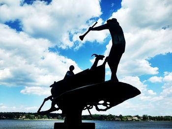 Silhouette man standing by lake against sky