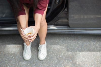 Low section of woman drinking coffee in car