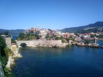 Town by sea against clear blue sky