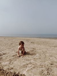 Small girl playing with sand on a beach in a foggy day 