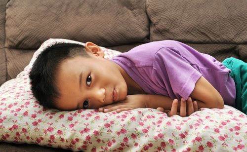 Side view portrait of boy lying on sofa