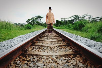 Full length of young man walking on railroad track against clear sky