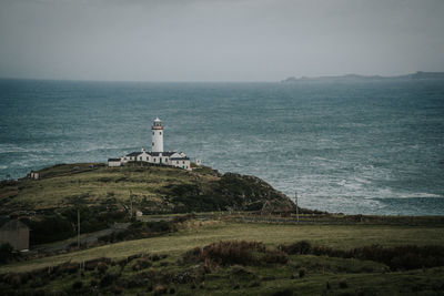 Lighthouse by sea against sky