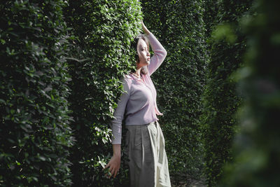 Woman standing by tree against plants