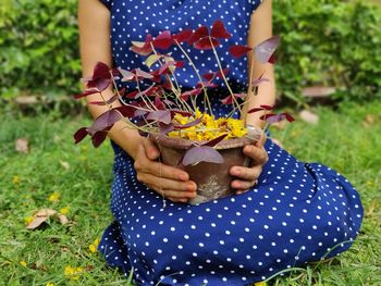 Midsection of woman holding plant on field