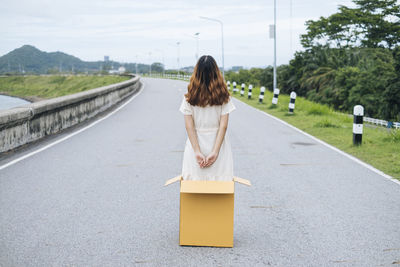 Rear view of woman with umbrella on road