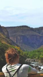 Rear view of woman standing on mountain against sky