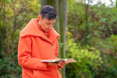 A woman in orange coat reading in the park