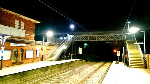 Illuminated railroad station against sky at night
