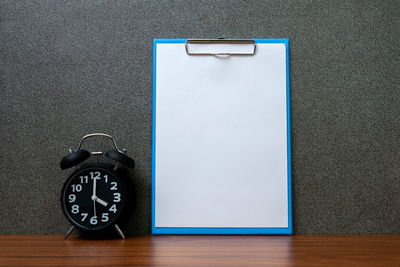 Close-up of clock on table against wall