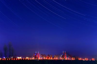 Illuminated bridge in city against clear blue sky at night