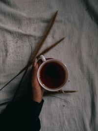 High angle view of hand holding tea cup on table