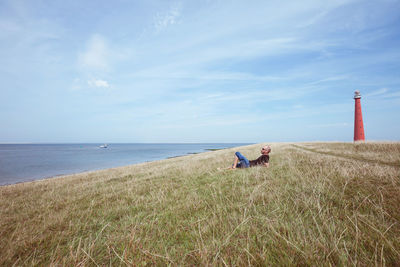 Man relaxing at beach against sky