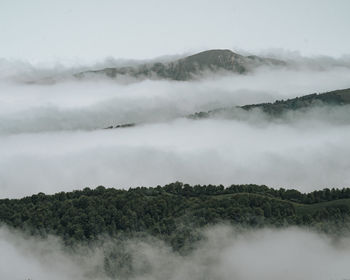 Scenic view of fog covered mountains against sky