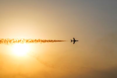 Low angle view of silhouette airplane flying against sky during sunset