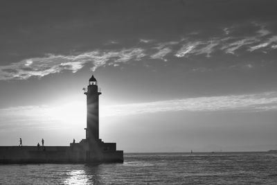 Lighthouse by sea against sky