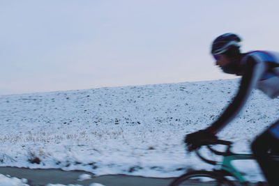 Man riding bicycle by sea against sky