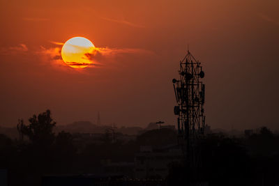 Silhouette of tower against cloudy sky during sunset