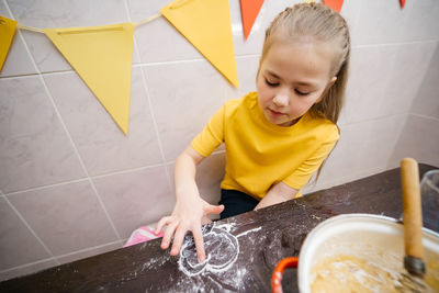 Girl draws a heart with flour, kneads dough for sweets