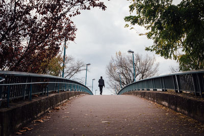 Rear view of woman walking on footbridge during autumn