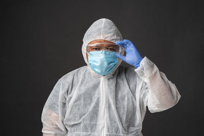 Portrait of doctor wearing mask against black background