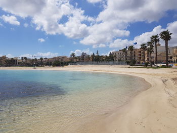 Scenic view of beach by buildings against sky