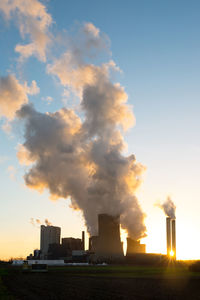 Smoke emitting from factory against sky