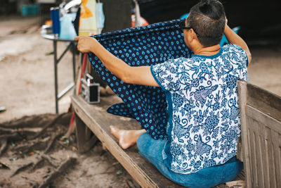 Rear view of woman sitting on wood