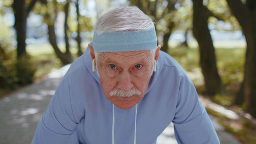 Portrait of confident senior man listening music on wireless in ear headphones