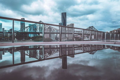 Bridge over river in city against sky