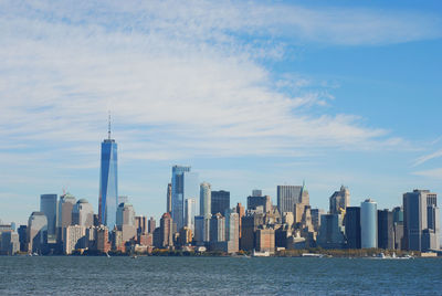 Gorgeous view of the manhattan skyline with the freedom tower over a calm sea on a sunny day