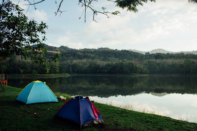 Scenic view of tent by lake against sky