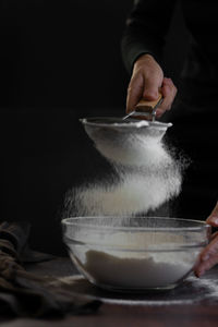Crop view of woman hands sifting flour through sieve