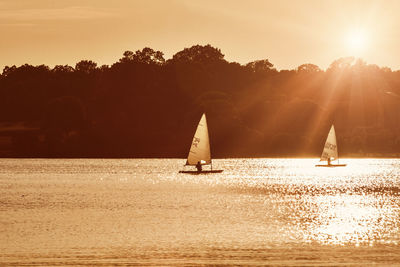 Silhouette sailboat sailing on sea against sky during sunset