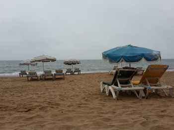 Deck chairs on beach against sky