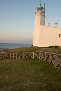 Lighthouse by sea against clear sky