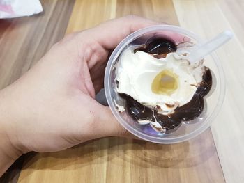 Cropped hand holding ice cream on wooden table