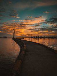 Pier over sea against sky during sunset