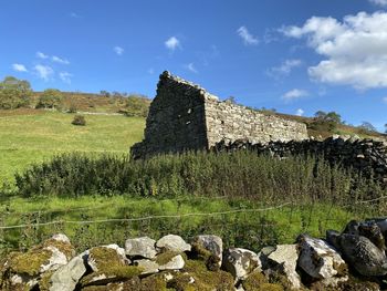 Old stone barn ruins, with a stone wall, in the foreground near, halton gill, skipton, uk