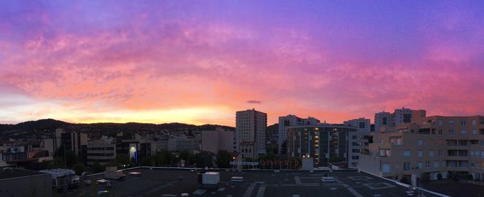 Cityscape against cloudy sky at sunset