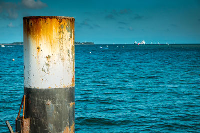 Close-up of wooden post in sea against sky