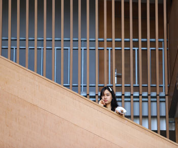 Portrait of woman sitting against brick wall