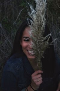 Portrait of smiling young woman holding dry plant