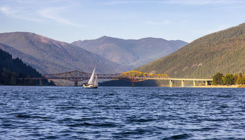 Sailboat on bridge over river against sky