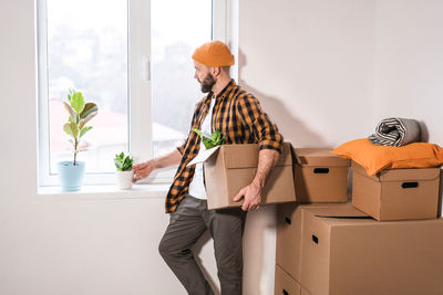 Mature man unpacking things from boxes while moving in new apartment.