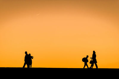 Silhouette men photographing against sky during sunset