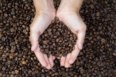 Copped hands of woman holding coffee beans