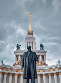 Low angle view of statue of building against cloudy sky