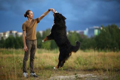 Full length of man playing with dog on grass